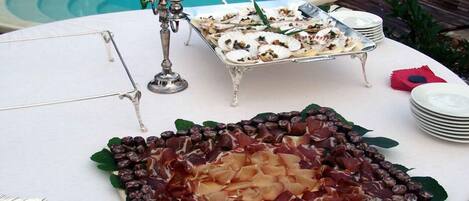 A table with a variety of food items, including a platter of cured meats and a tray of seafood.