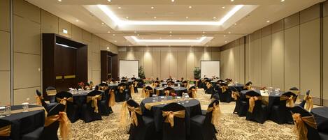A conference room with round tables, black chairs, and gold sashes.