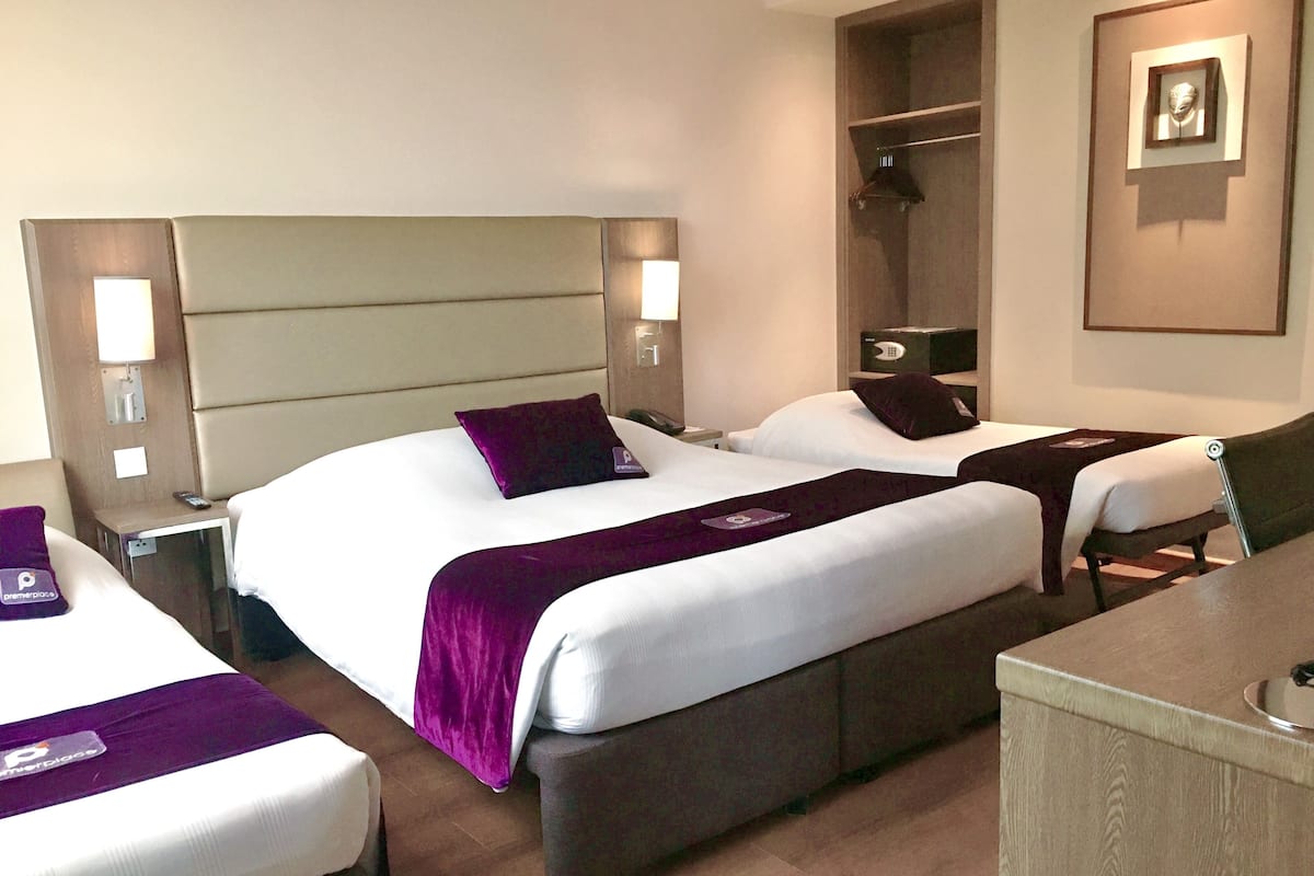 Habitación de hotel con dos camas, un escritorio y un armario.