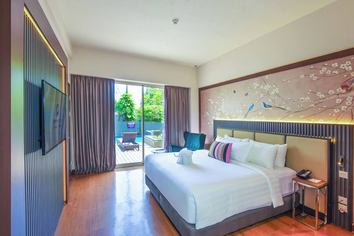 Habitación de hotel con una cama grande, televisión, escritorio y vistas al exterior.