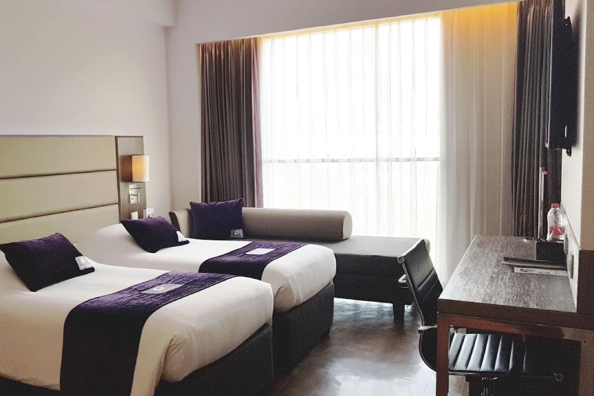 Una habitación de hotel con dos camas, un sofá, un escritorio y una silla.
