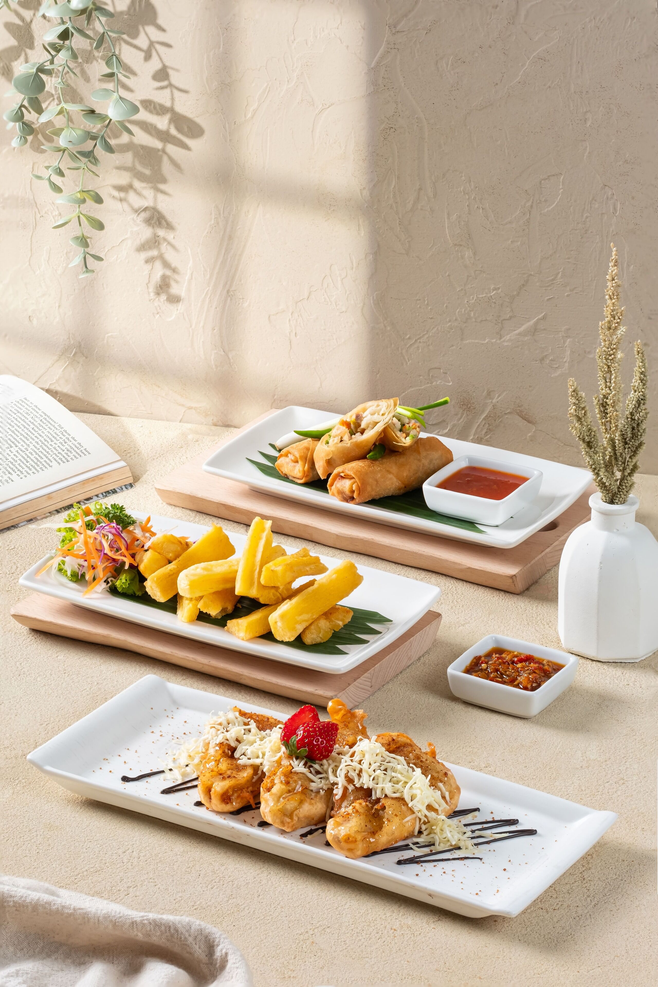 A table with various dishes, including fried items and a plate with a dessert topped with a strawberry.