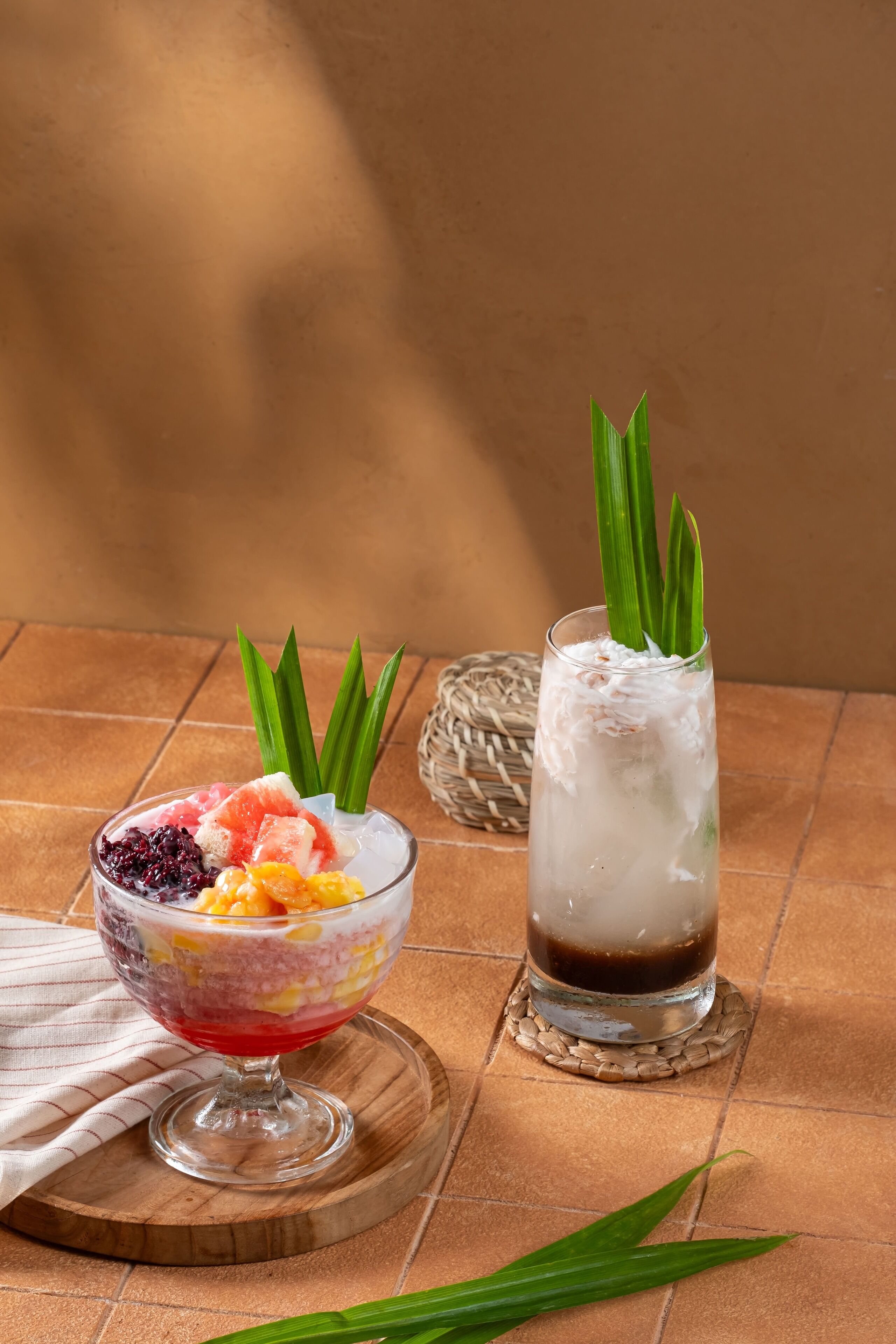 Dos bebidas sobre una tabla de madera con un tapete tejido debajo.