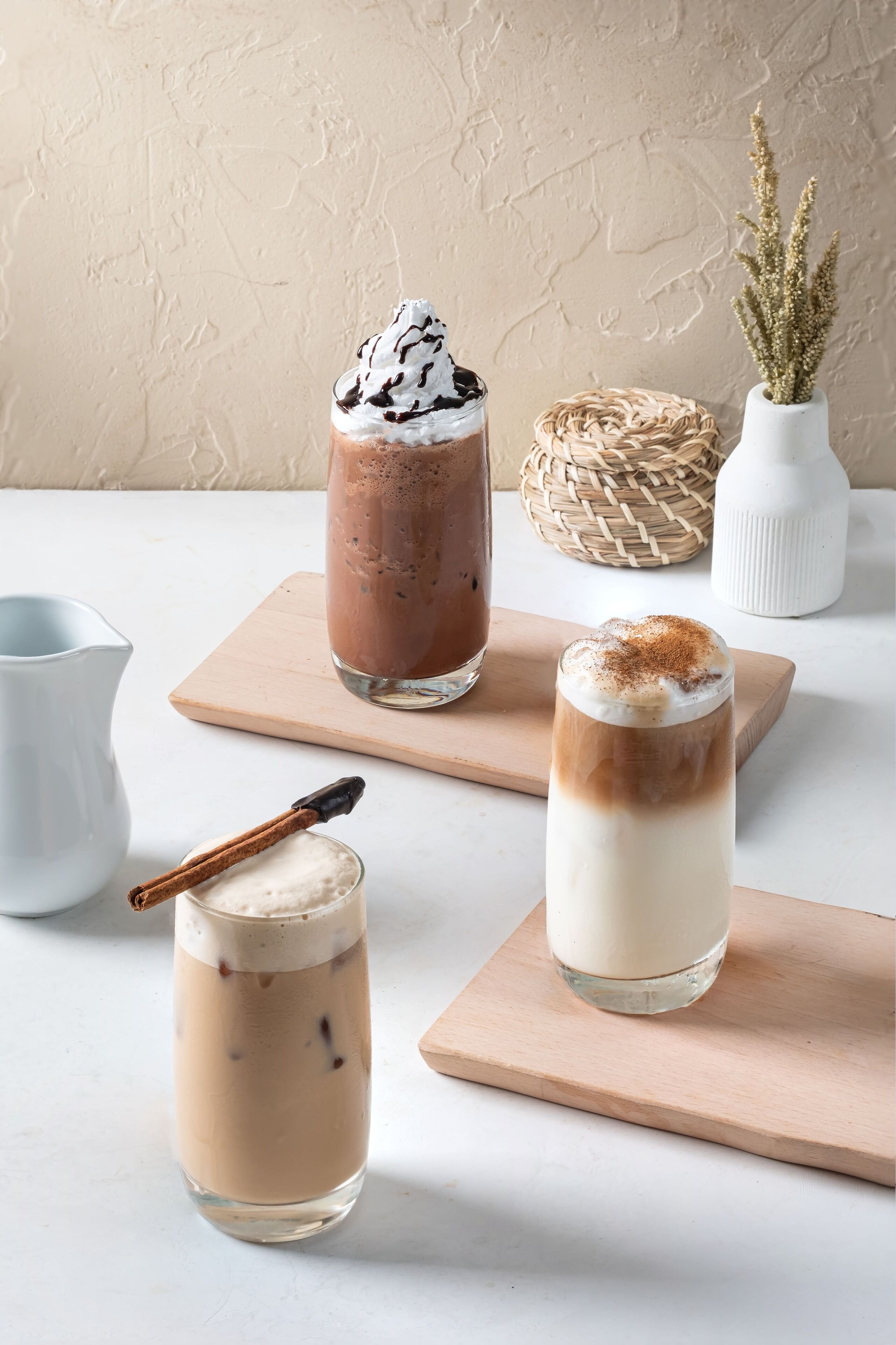 Three glasses of iced coffee on wooden boards.