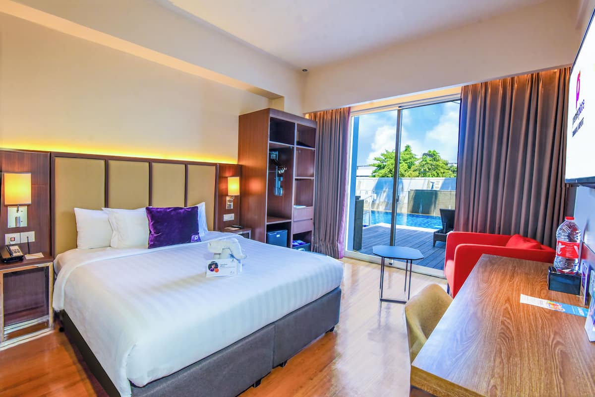 Une chambre d’hôtel avec un grand lit, un bureau, une chaise, une armoire et une vue sur l’extérieur.