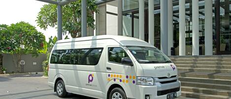 A white van parked in front of a modern building with large glass windows and columns.