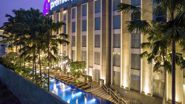 Un hôtel doté d’une piscine, de palmiers et d’une enseigne indiquant « Premier Place ».