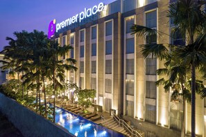 Un hotel con piscina, palmeras y un letrero que dice "Premier Place".