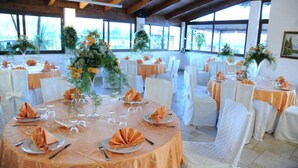 A banquet hall with round tables set for a formal event, featuring white chairs and orange tablecloths. - L'Oasi del Fauno Country House (Casal Velino)