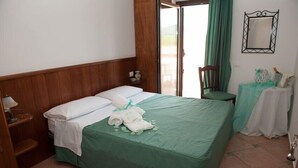 A bedroom with a bed, a chair, a small table, and a mirror on the wall. - L'Oasi del Fauno Country House (Casal Velino)