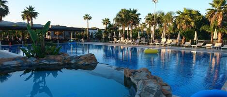 Una piscina al aire libre de temporada, sombrillas, tumbonas