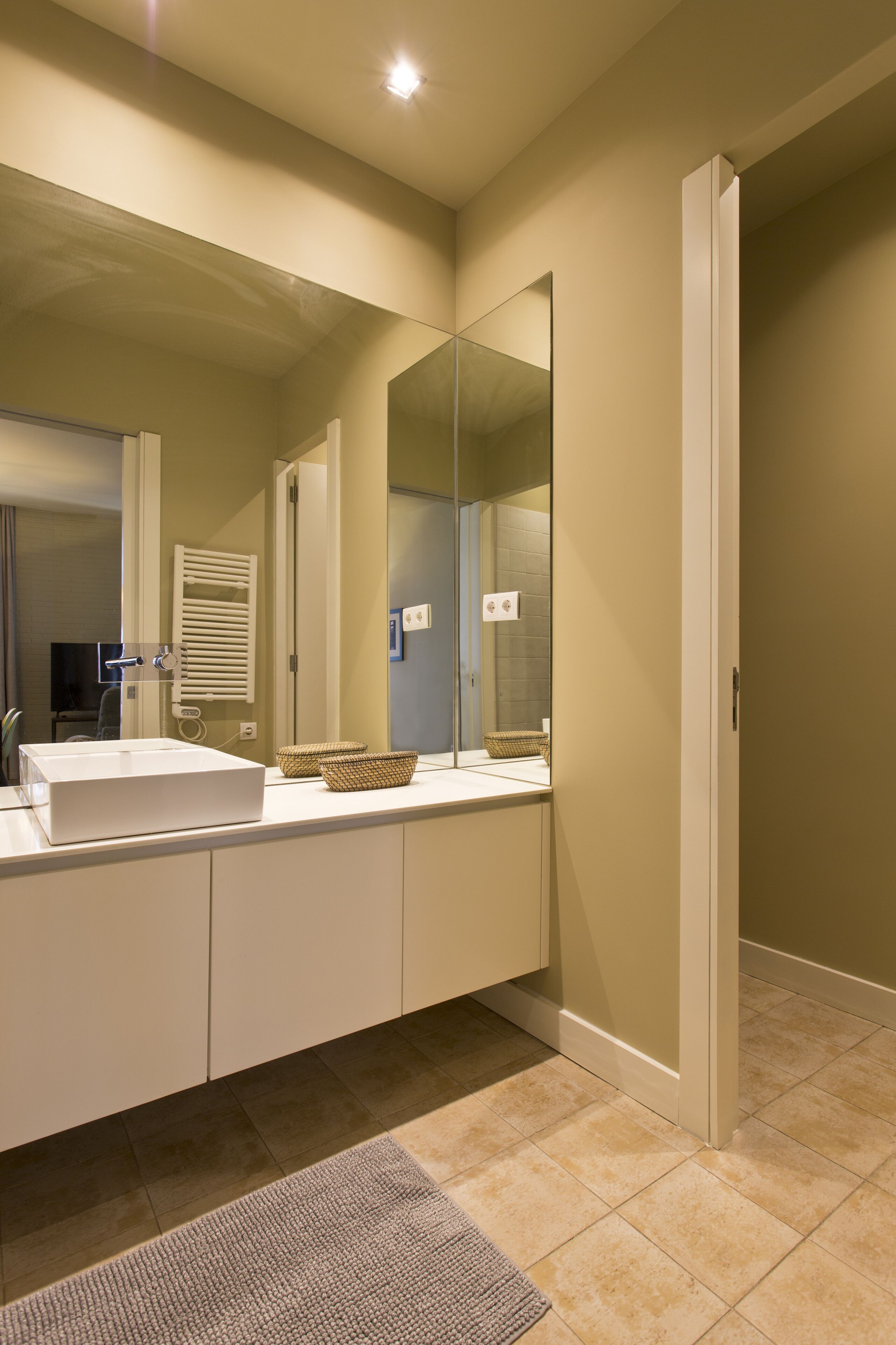 A modern bathroom with a large mirror, a sink, and a towel rack.