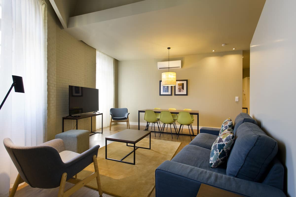 A modern living room with a sofa, chairs, a coffee table, and a TV.