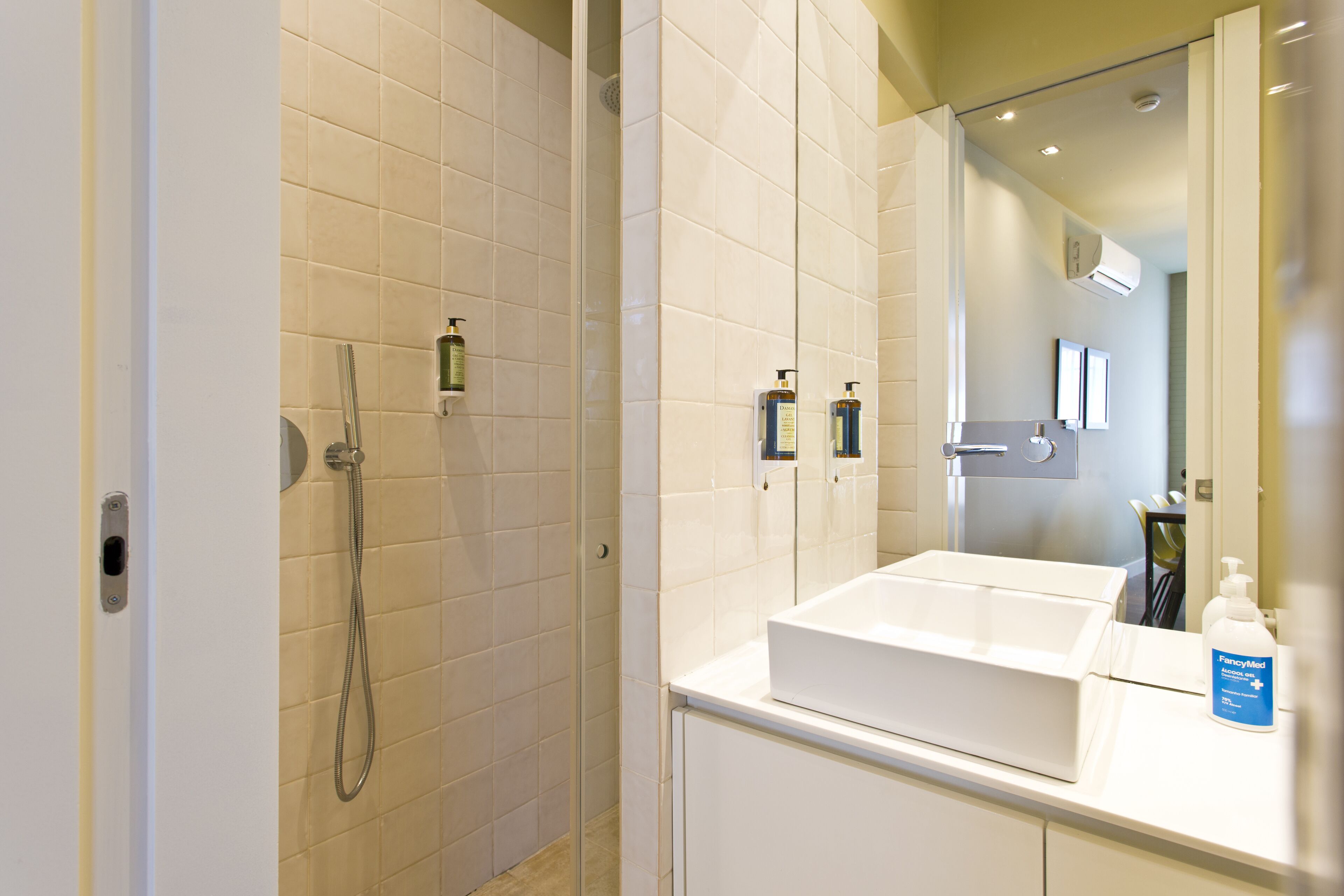Un bagno moderno con uno specchio grande, un lavandino bianco e una zona doccia.