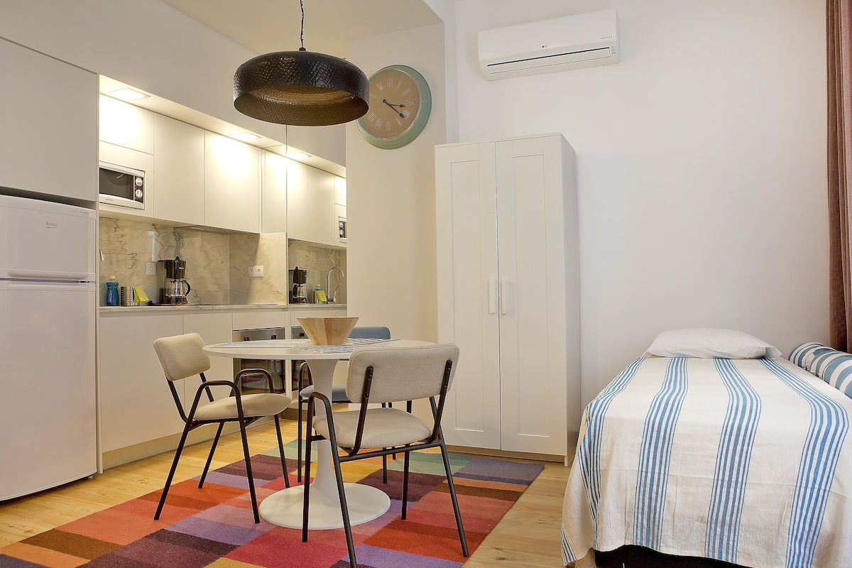 A compact kitchen with a microwave, a sink, and a dining area with chairs and a table.