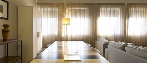 A dining area with a wooden table, a floor lamp, and a sofa.