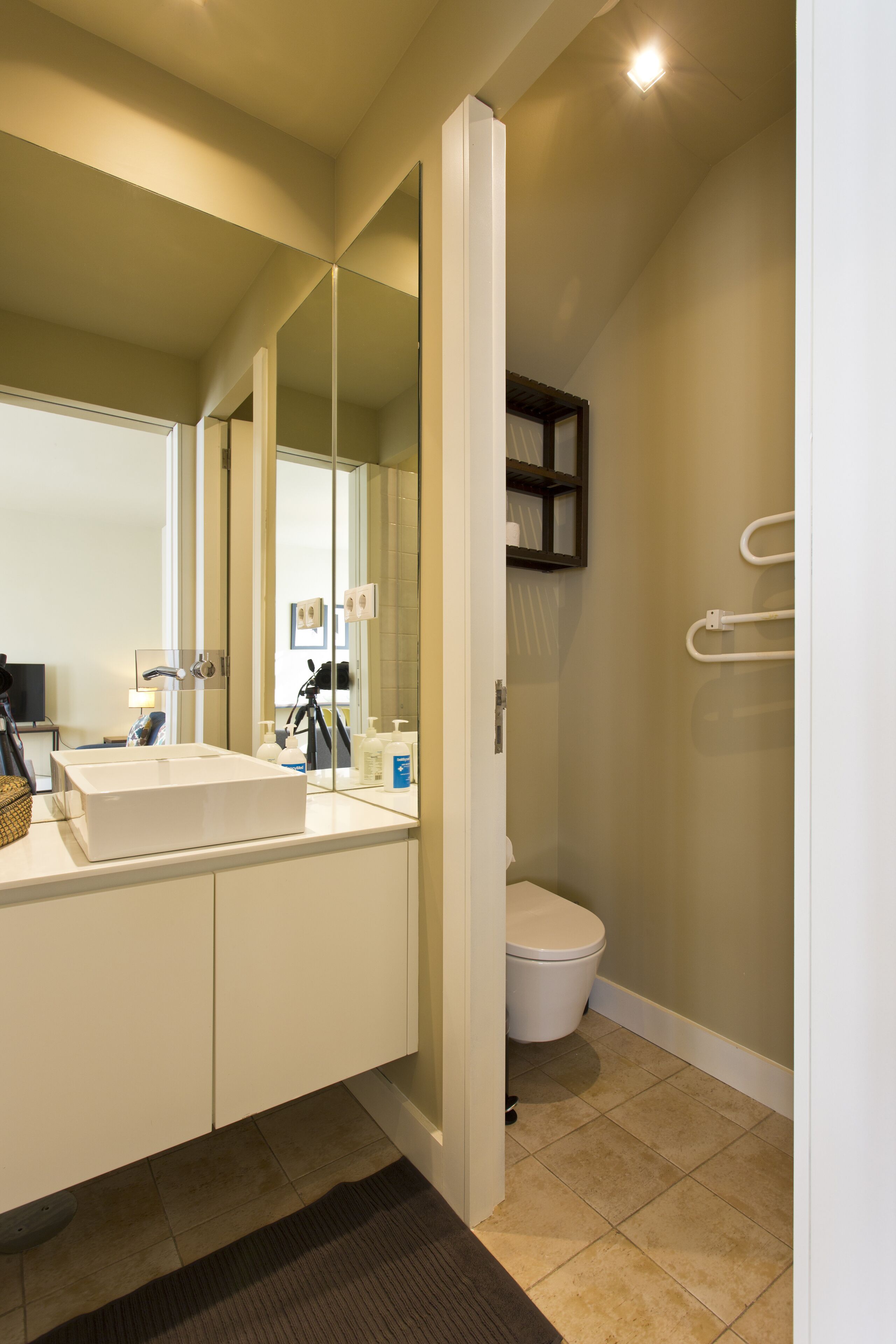 Un bagno moderno con un grande specchio, un lavandino bianco e un water.
