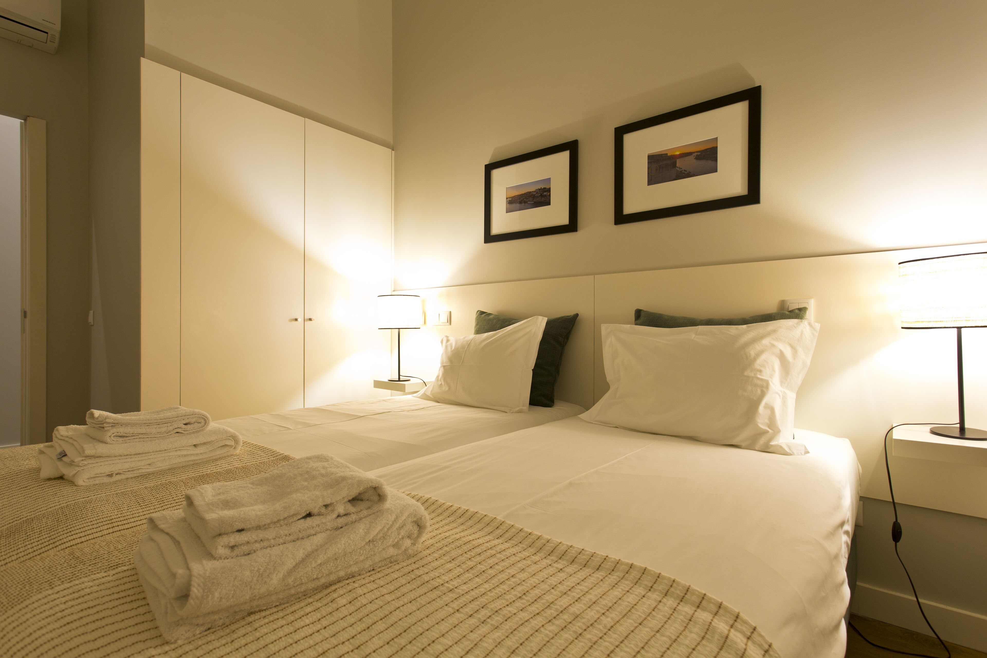 Ein Hotelzimmer mit zwei Betten, einem großen Kleiderschrank und zwei an der Wand befestigten Bildern.