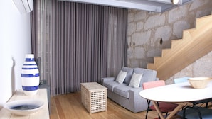 A modern living room with a grey sofa, a wooden coffee table, and a striped vase. - RVA Porto Central Flats (Porto)