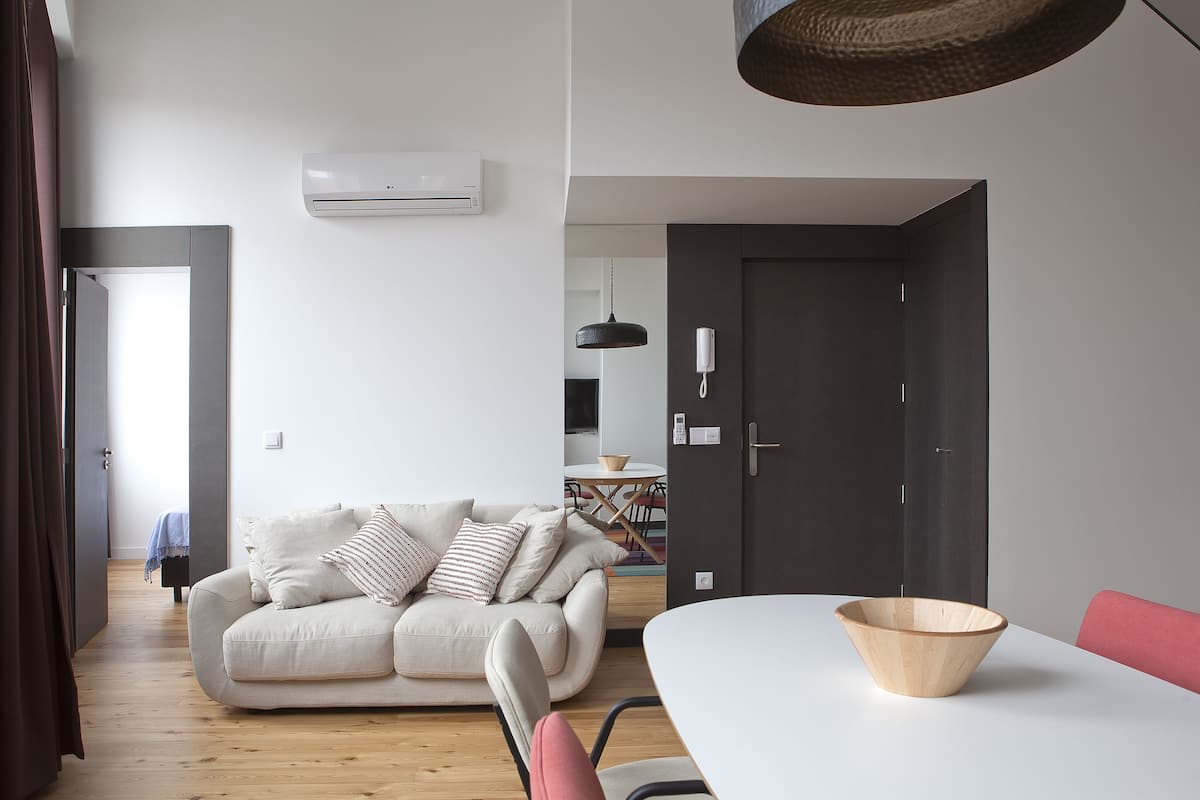 A modern living room with a sofa, a dining table, and a wooden bowl.