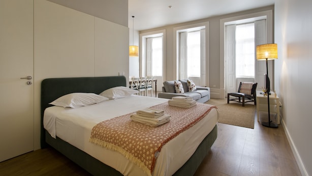 A well-lit bedroom with a large bed, a desk, and a chair. - RVA Porto Central Flats (Porto)