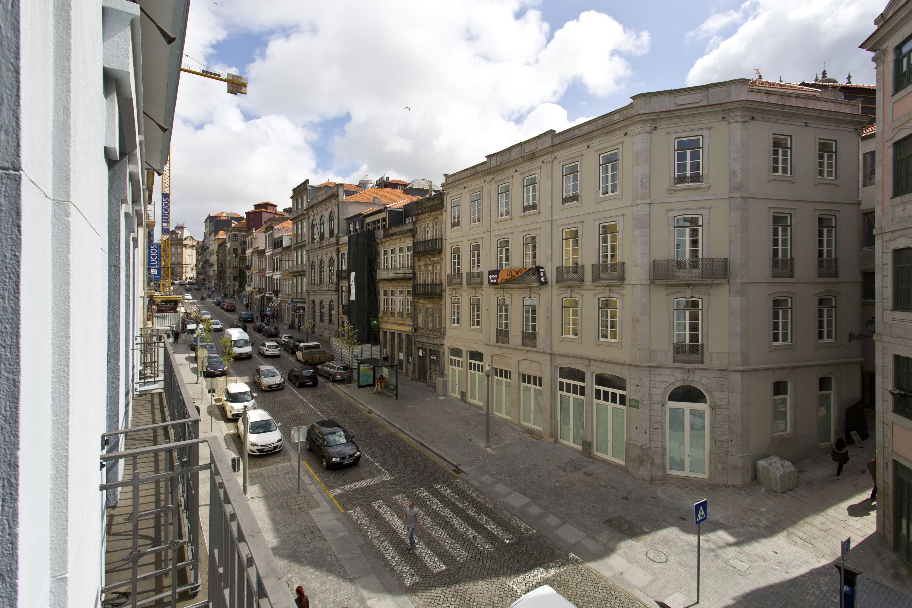 A street view with buildings, cars, and a pedestrian crossing.