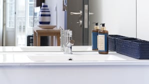A modern bathroom with a large mirror, a white sink, and two bottles of shampoo. - RVA Porto Central Flats (Porto)