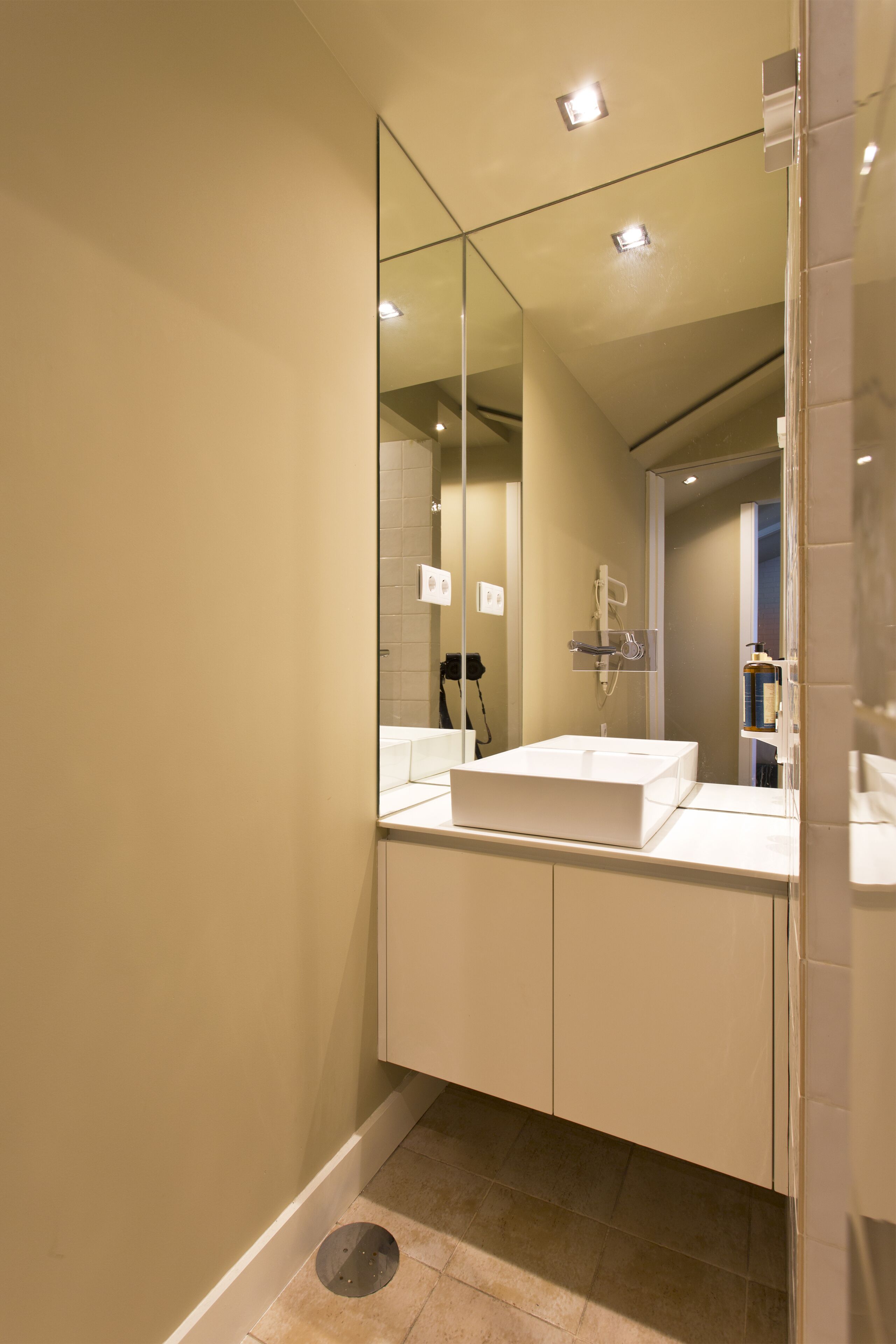 A modern bathroom with a large mirror, a white sink, and a shower area.