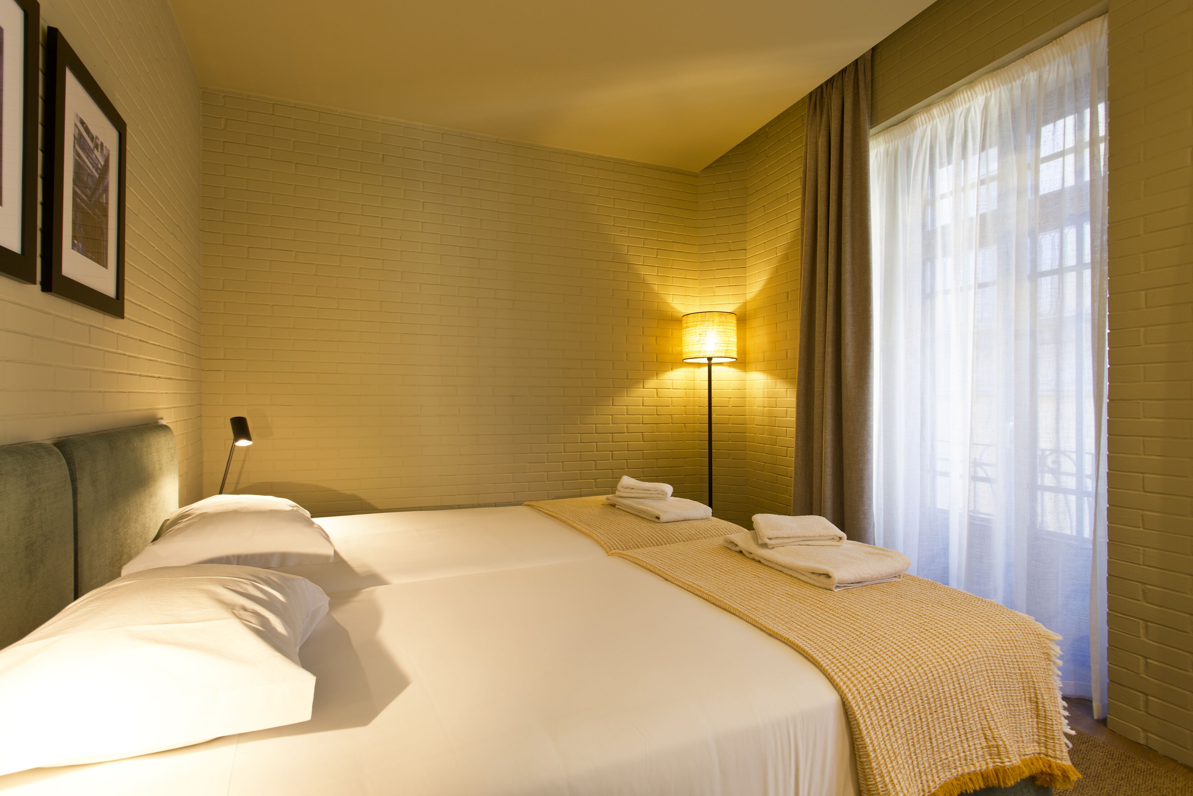 A hotel room with a large bed, a bedside lamp, and a window with curtains.