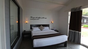 Una camera d'hotel con un letto grande, una testiera con una citazione, lampade sui comodini e vista dalla finestra.