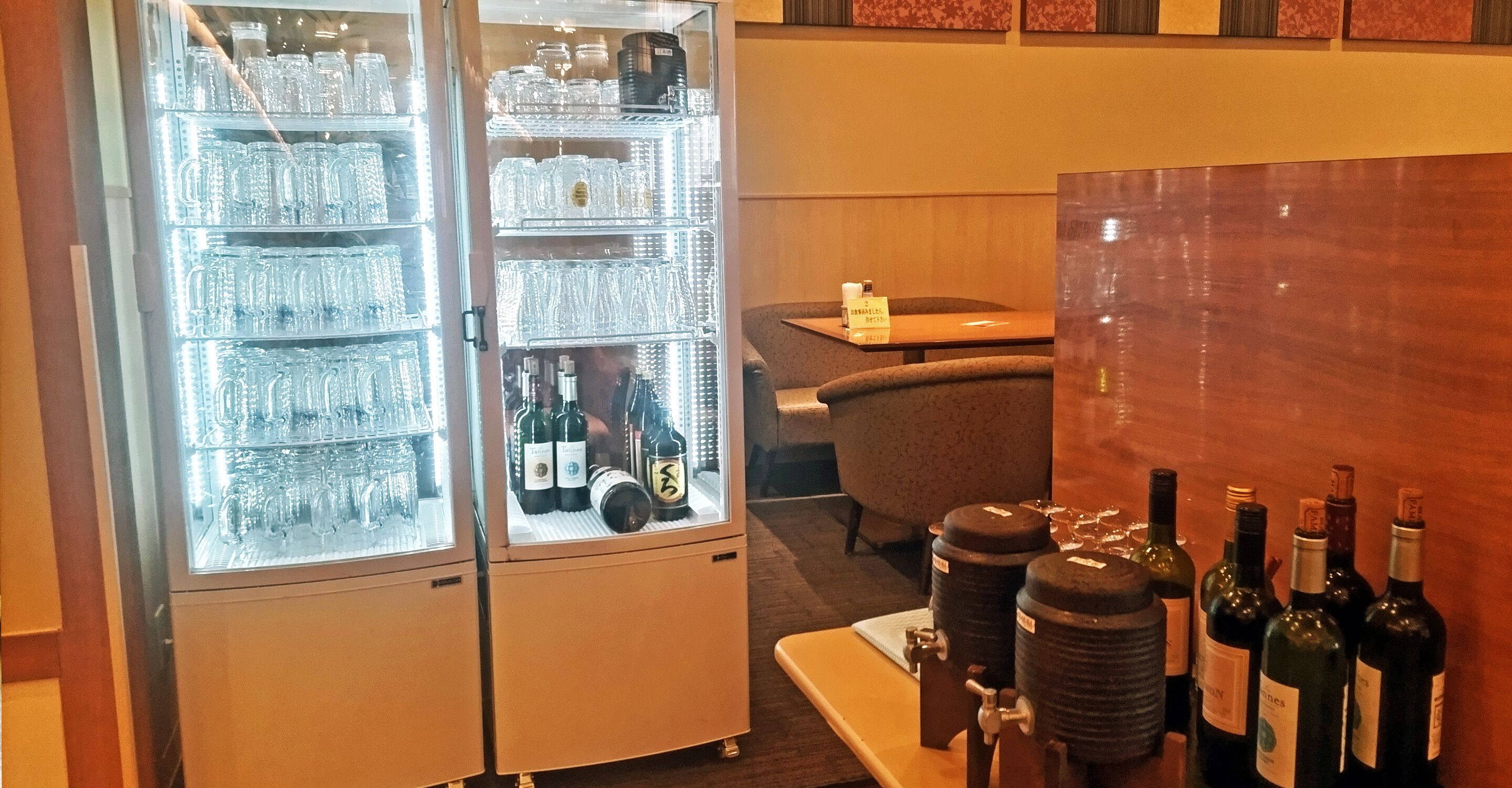 A minibar with a refrigerator and shelves of glasses and bottles.