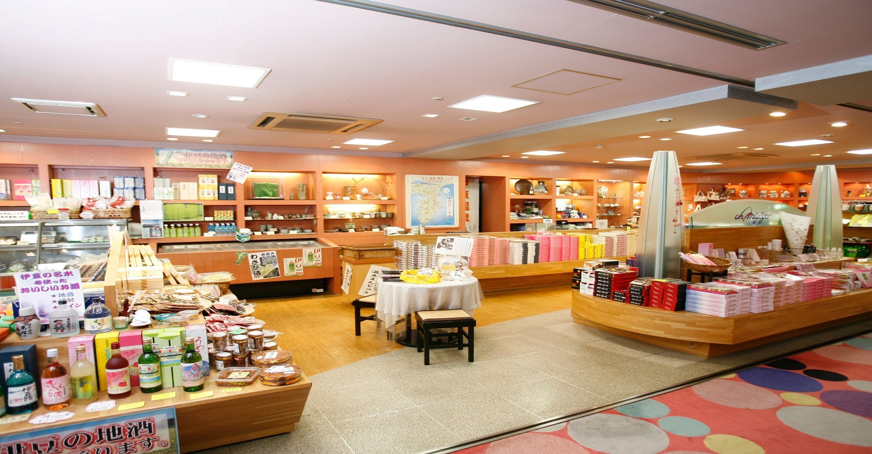 A store interior with shelves stocked with various products, a display table with items, and a counter with a menu.