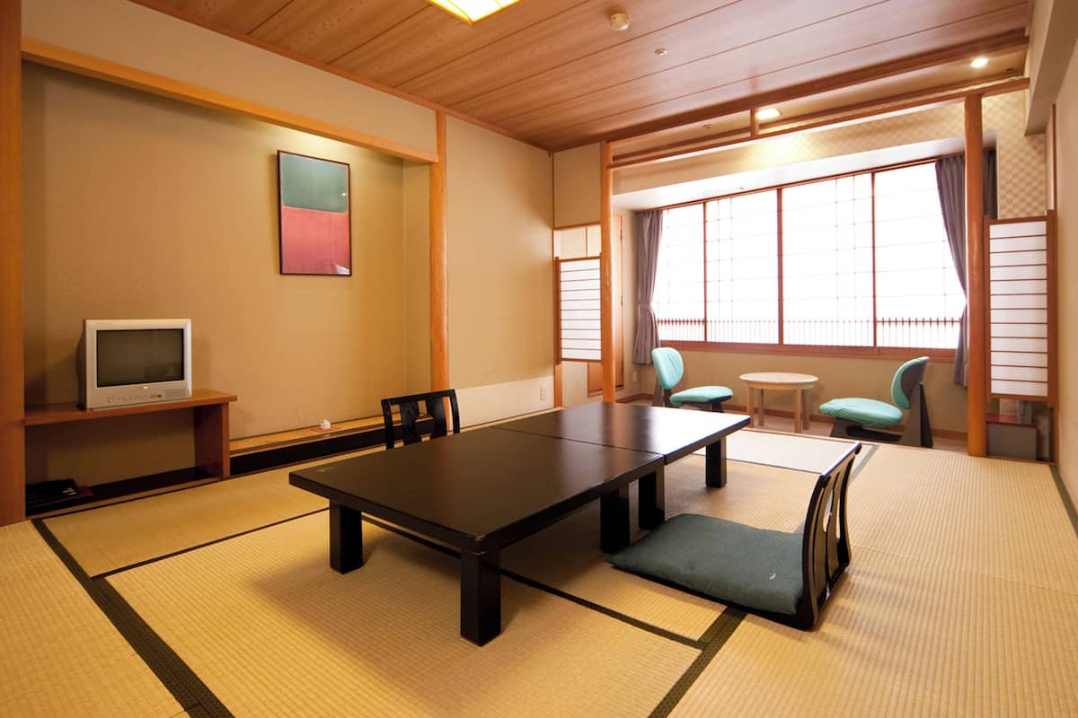 Quarto em estilo japonês tradicional, com tatames, uma mesa baixa e duas cadeiras.
