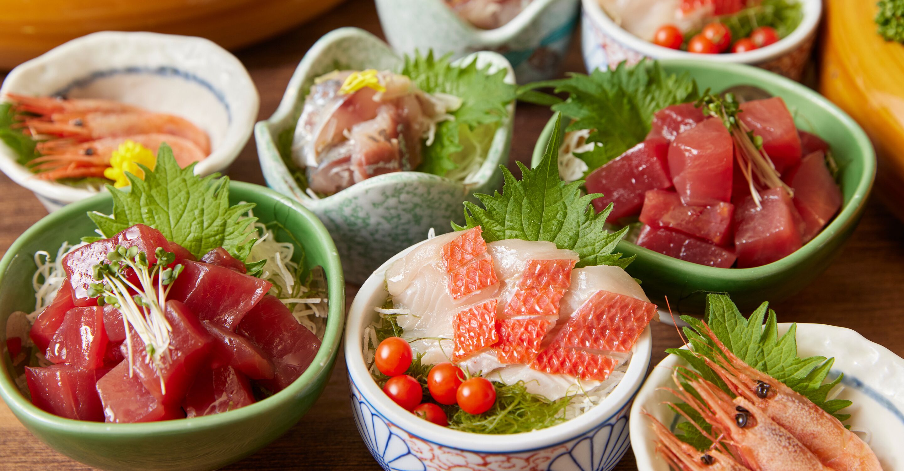 A variety of sashimi dishes in small bowls, each with different types of fish and garnishes.
