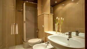 A modern bathroom with a walk-in shower, a toilet, a bidet, and a sink with a mirror. - Amalia Suites (Rome)