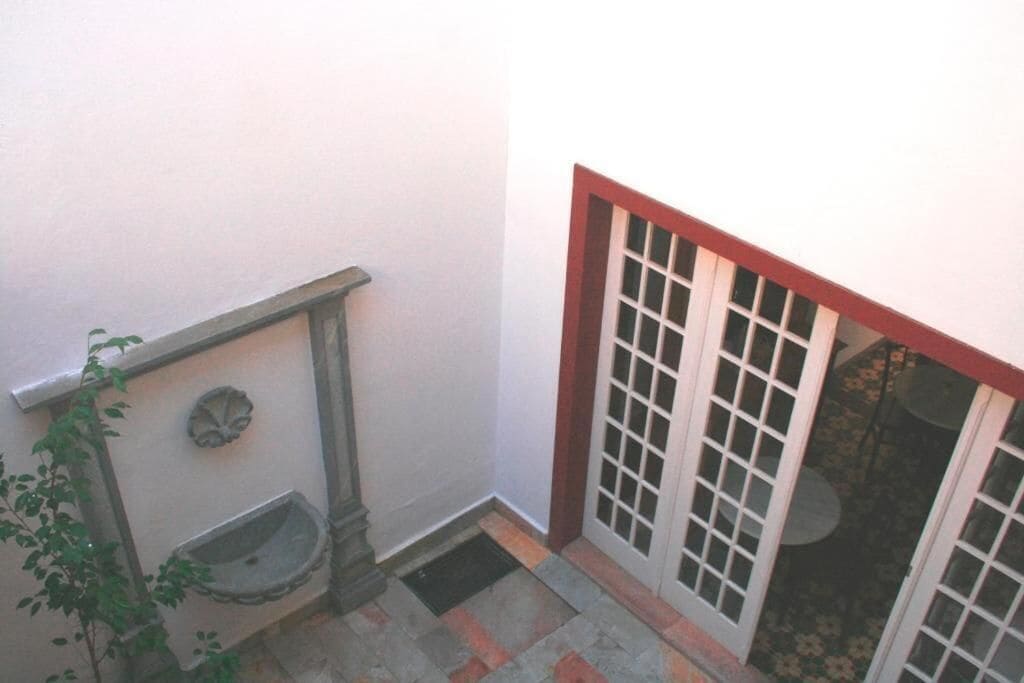 A narrow stairway with a handrail, a small outdoor sink, and a door with glass panels.