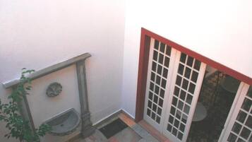 A narrow stairway with a handrail, a small outdoor sink, and a door with glass panels.