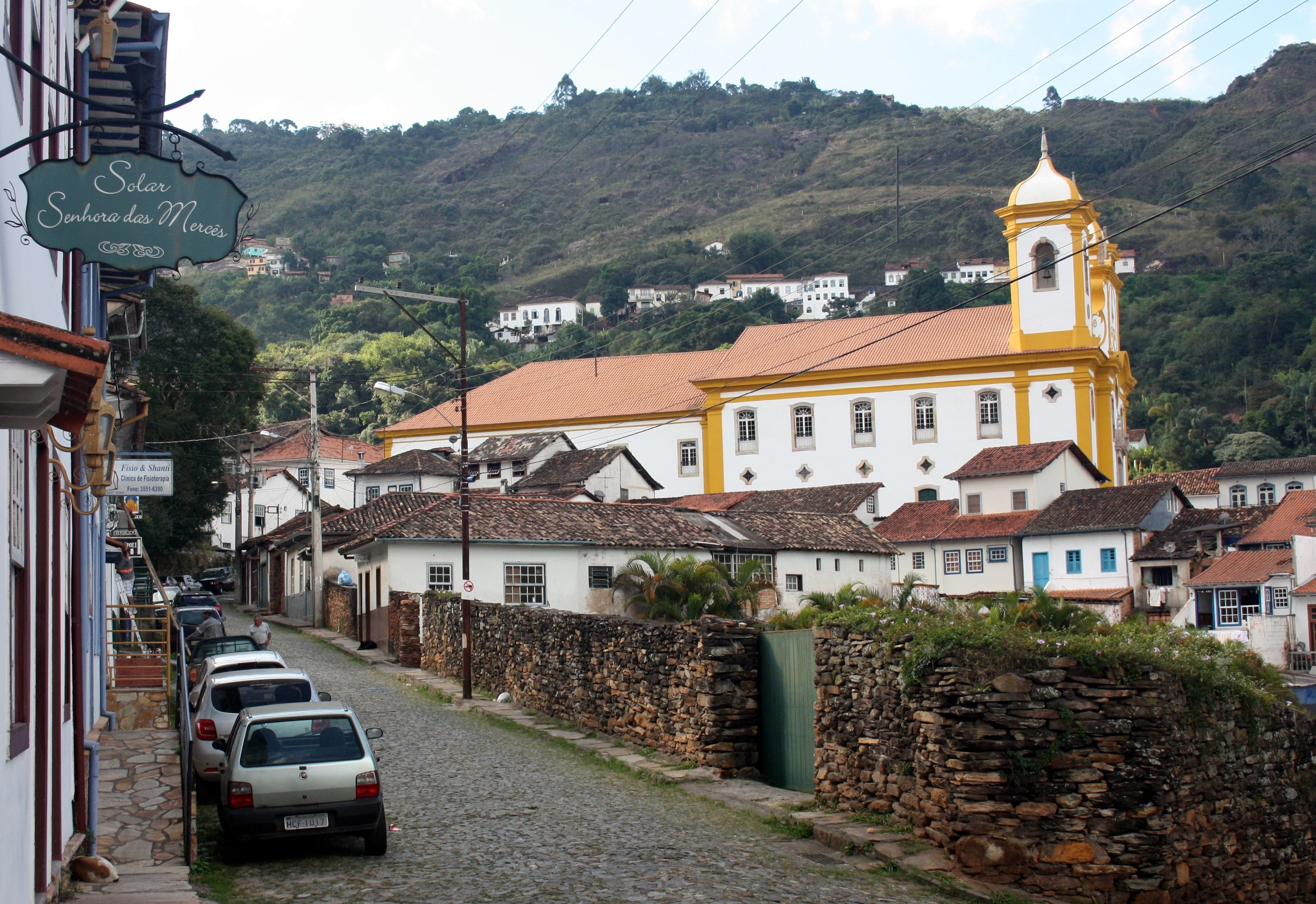 Una calle adoquinada con una iglesia amarilla y edificios blancos.