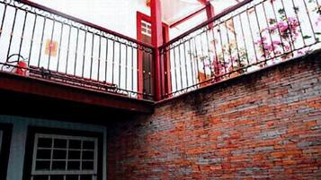 Un bâtiment en briques avec une rambarde métallique rouge et une fenêtre.