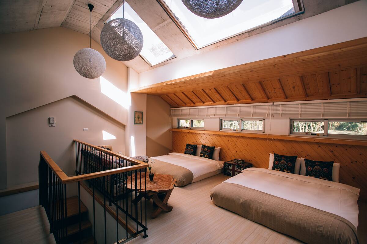 A loft-style bedroom with a wooden ceiling, skylights, and a staircase.
