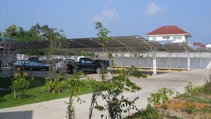 Un espace de stationnement doté d’une structure abritée, un bâtiment avec un toit rouge et quelques véhicules.