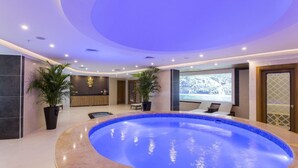 A modern indoor swimming pool with a circular design, surrounded by seating areas and a reception desk. - Michell Hotel & Spa (Alanya)