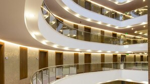A multi-level atrium with curved balconies, glass railings, and a red carpeted area. - Michell Hotel & Spa (Alanya)