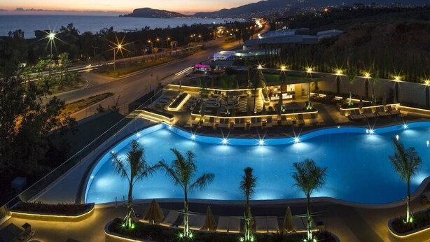 A resort with a large swimming pool, lounge areas, and a view of the sea at dusk. - Michell Hotel & Spa (Alanya)