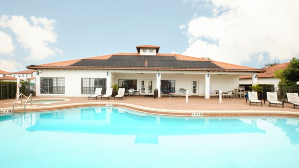 Ein Swimmingpool mit Liegestühlen und einer überdachten Terrassenbereiches.