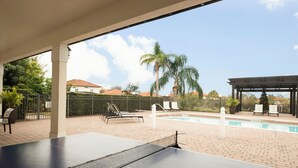 Ein Billardtisch mit Netz, Sitzgelegenheiten im Freien und ein Poolbereich.