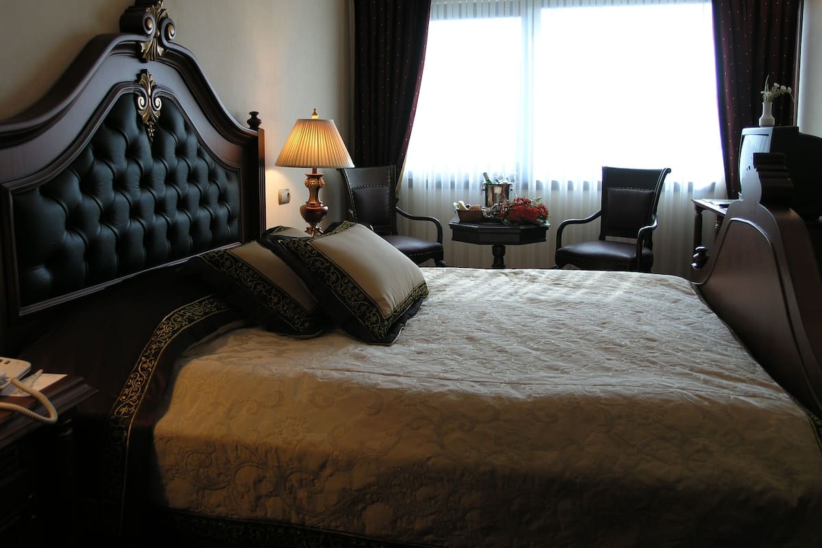 Habitació d'hotel amb un llit gran, un escriptori, una cadira i una finestra amb cortines.