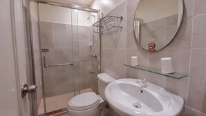 Une salle de bain moderne avec une douche à parois de verre, des toilettes, un lavabo et un miroir.