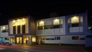 Un hôtel moderne, reconnaissable à son grand panneau lumineux, à ses larges fenêtres et à son entrée bien éclairée.
