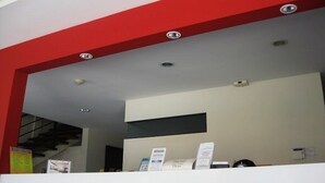 Un comptoir d’accueil avec un mur d’accent rouge, un comptoir blanc et plusieurs panneaux d’affichage.